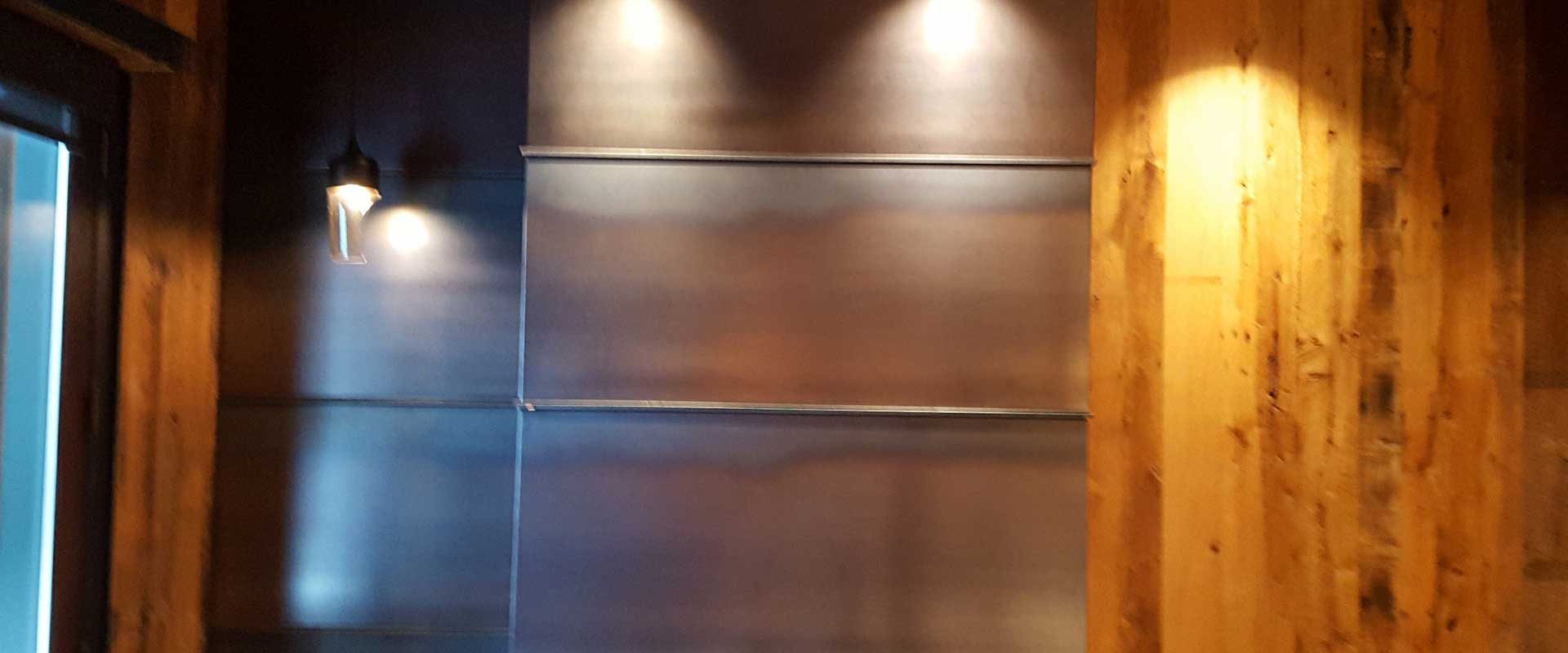 Empty metal wall shelves with spotlights above, wood paneling on the right, and a wall-mounted lamp on the left.