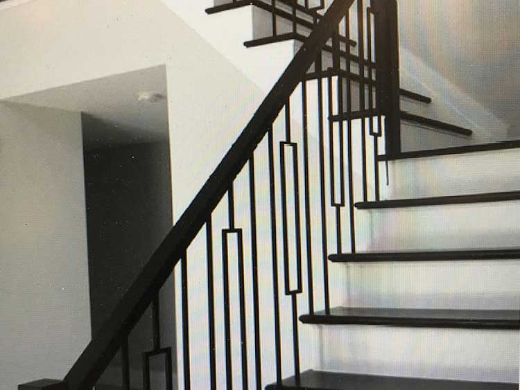 modern indoor staircase with black geometric metal railing and white walls.
