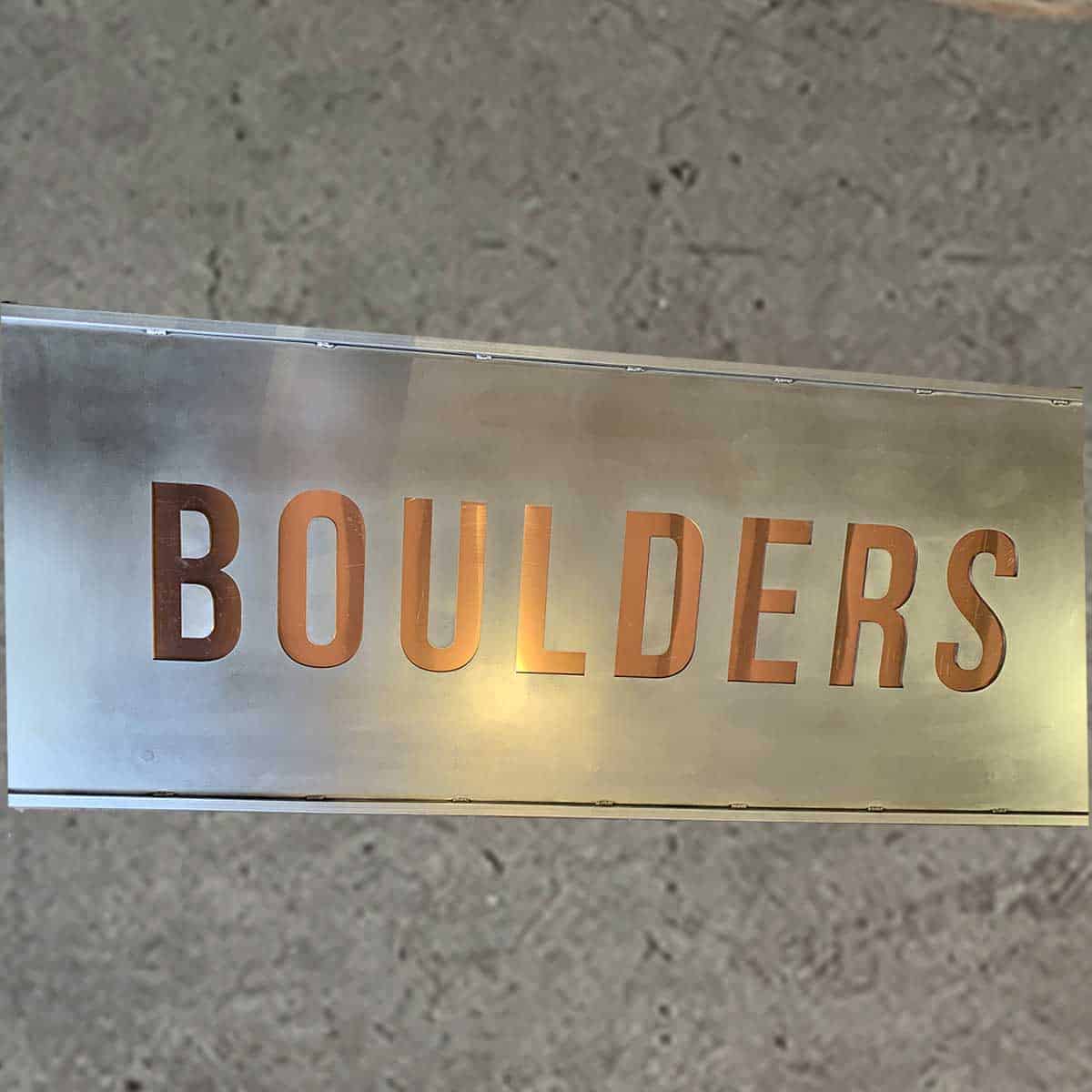 A metallic sign with the word "BOULDERS" cut out in large, capital letters.